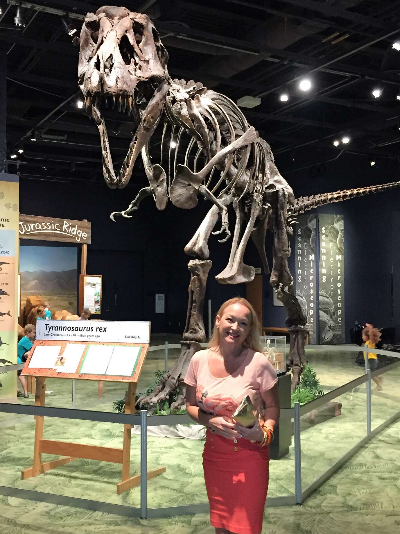 A person standing in front of a dinosaur skeleton Description automatically generated with medium confidence