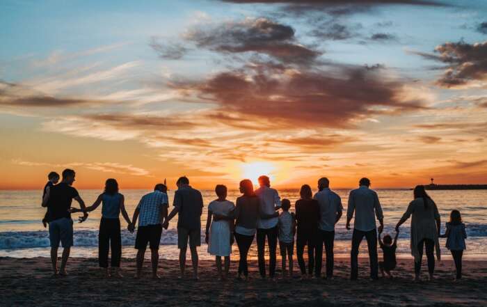 A group of people standing on a beach Description automatically generated with medium confidence